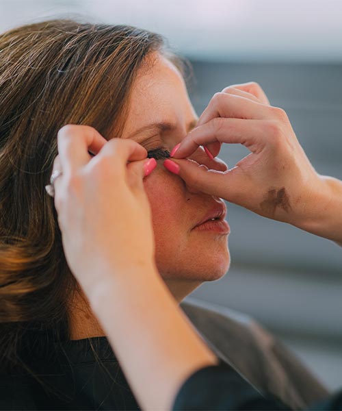 Makeup artist puts eyelashes on client