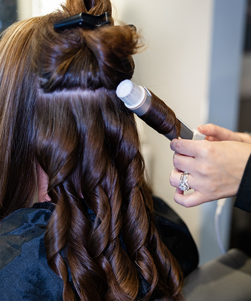 Dark haired girl getting her hair curled with beautiful bouncy curls